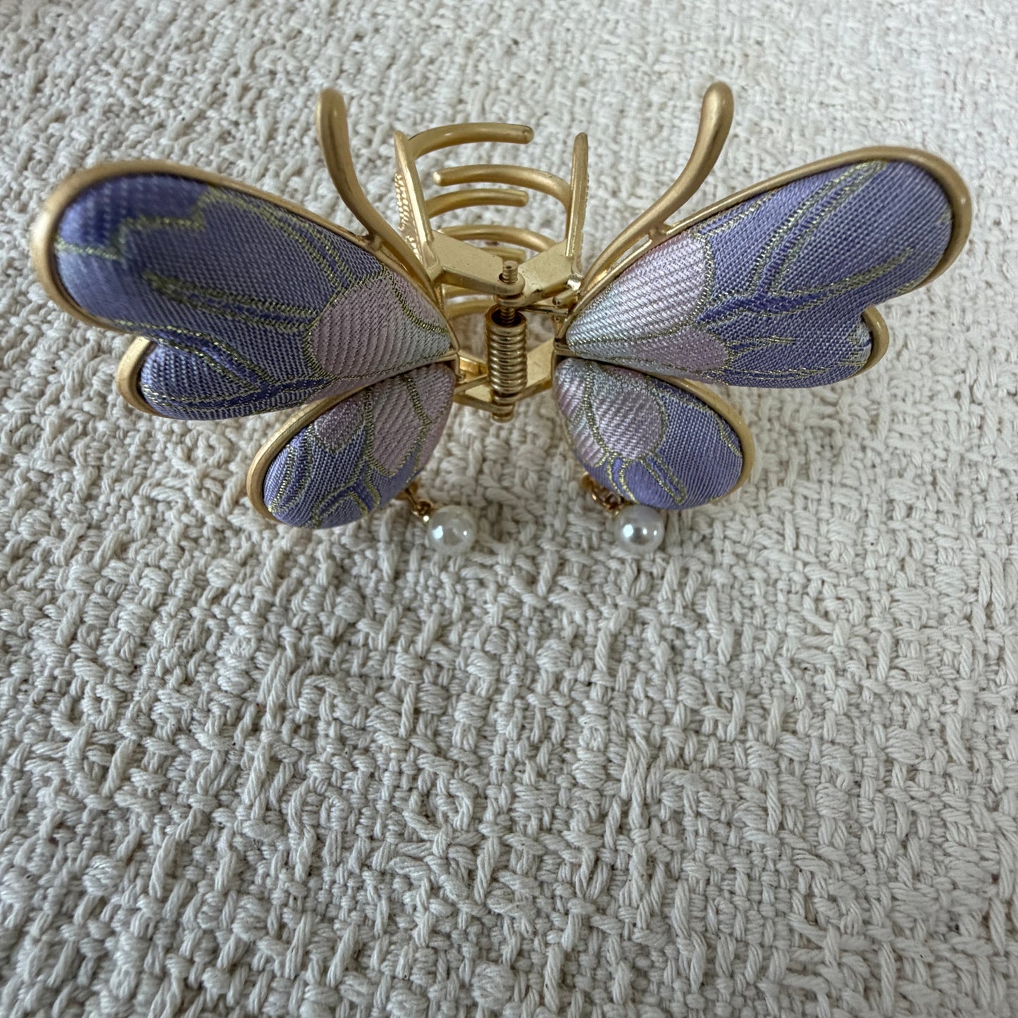 Lavender Butterfly Hair Claw Clip with Pearl-Effect Drops by JOFAE Kyoto. Four-wing butterfly silhouette; Lavender patterned textile; Two pearl-effect drops; Gold-tone antennae and claw frame.