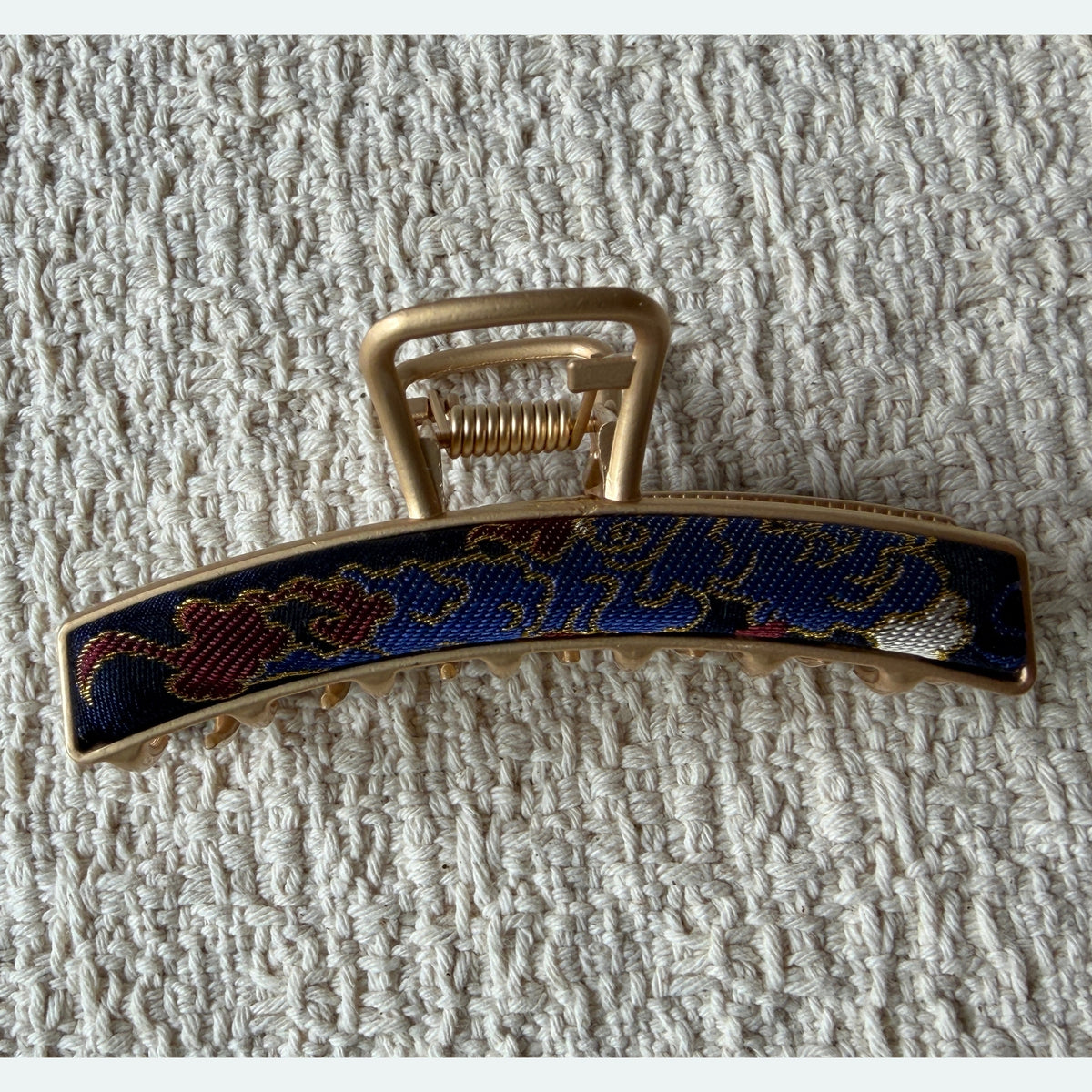 Navy Curved Bar Hair Claw Clip by JOFAE Kyoto. Curved rectangular bar silhouette; Navy multicoloured patterned textile; Squared ends; Gold-tone claw frame.