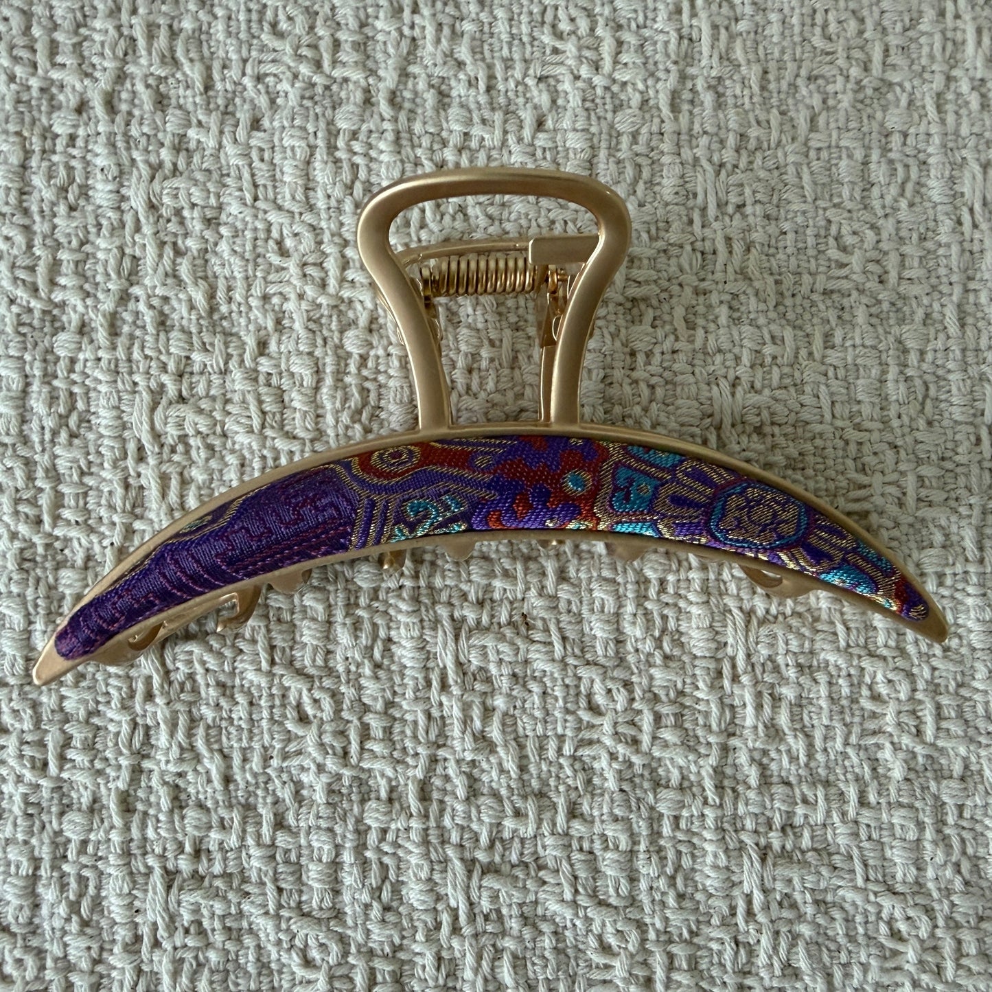 Purple Crescent Bar Hair Claw Clip by JOFAE Kyoto. Slim crescent bar silhouette; Purple multicoloured patterned textile; Tapered ends; Gold-tone claw fastening.