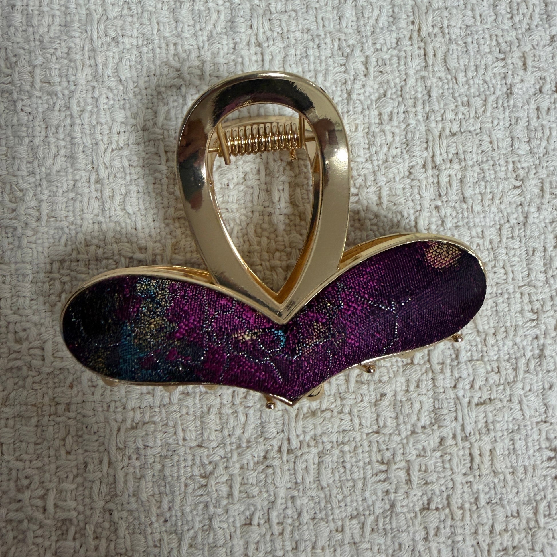 Plum Curved Bar Hair Claw Clip by JOFAE Kyoto. Curved bar silhouette with rounded ends; Deep plum patterned textile; Gold-tone outline; Open-loop claw handle.