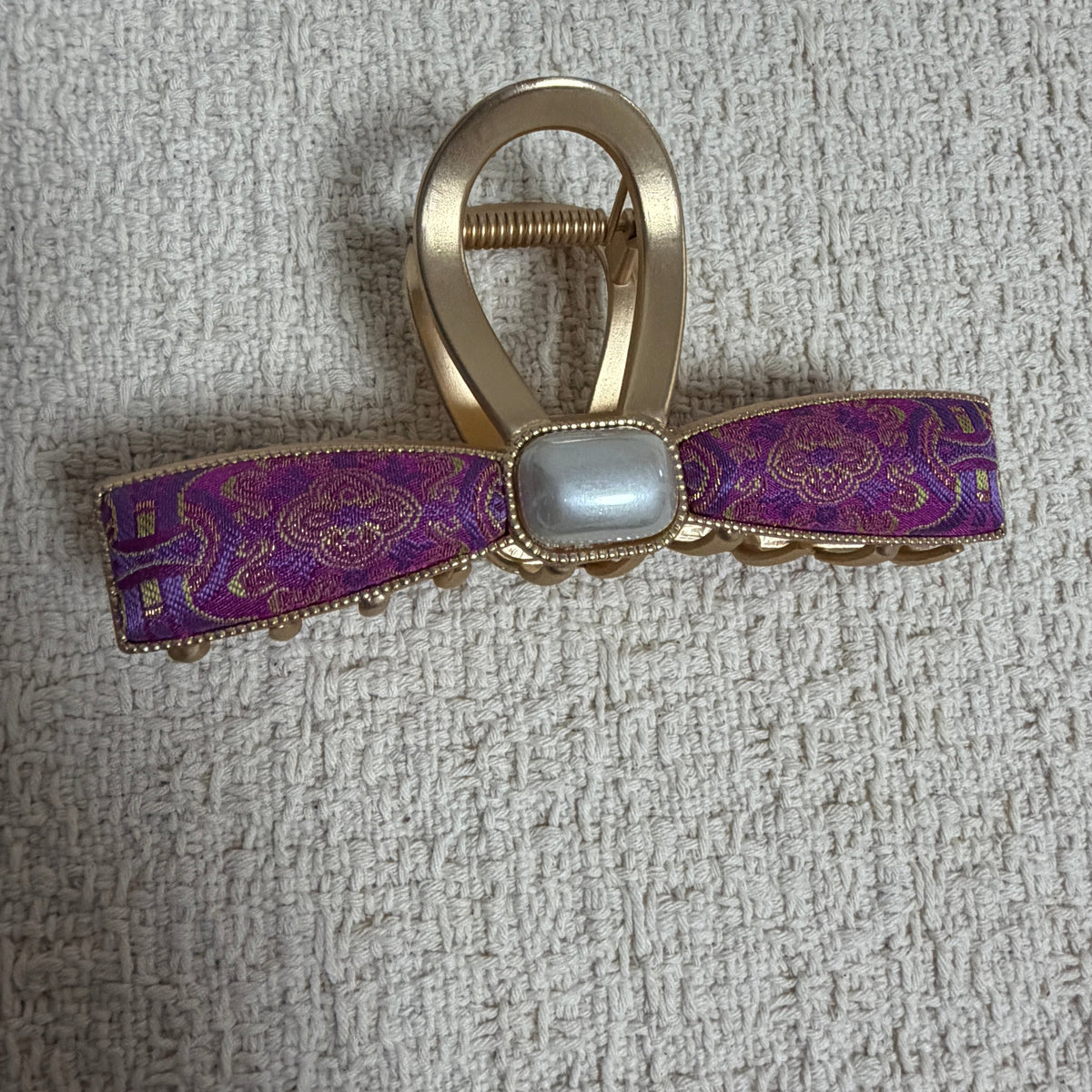 Purple Ribbon Bow Hair Claw Clip by JOFAE Kyoto. Slim ribbon bow silhouette; Purple patterned textile detail; Rectangular pearlescent centre; Gold-tone claw fastening.